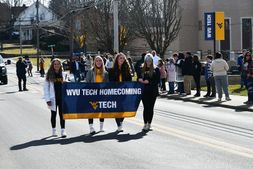 An image of four students carrying a banner that states WVU Tech Homecoming in a parade