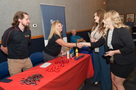 An image of two female students speaking with employers about available job opportunities.