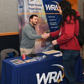 A student and an employer shaking hands at a job fair.