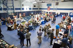 An overhead view of a career fair with vendor booths set up and students and employers interacting with each other. 